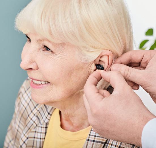 Frau beim Einsetzen eines Im-Ohr-Hörgeräts.
